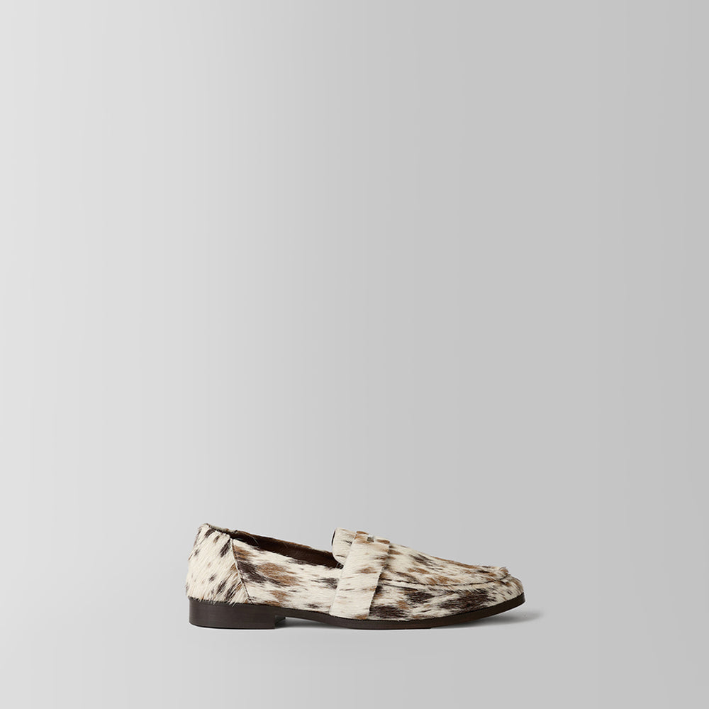 A single loafer in a brown and beige animal print pattern, shown in a side profile against a light gray background.
