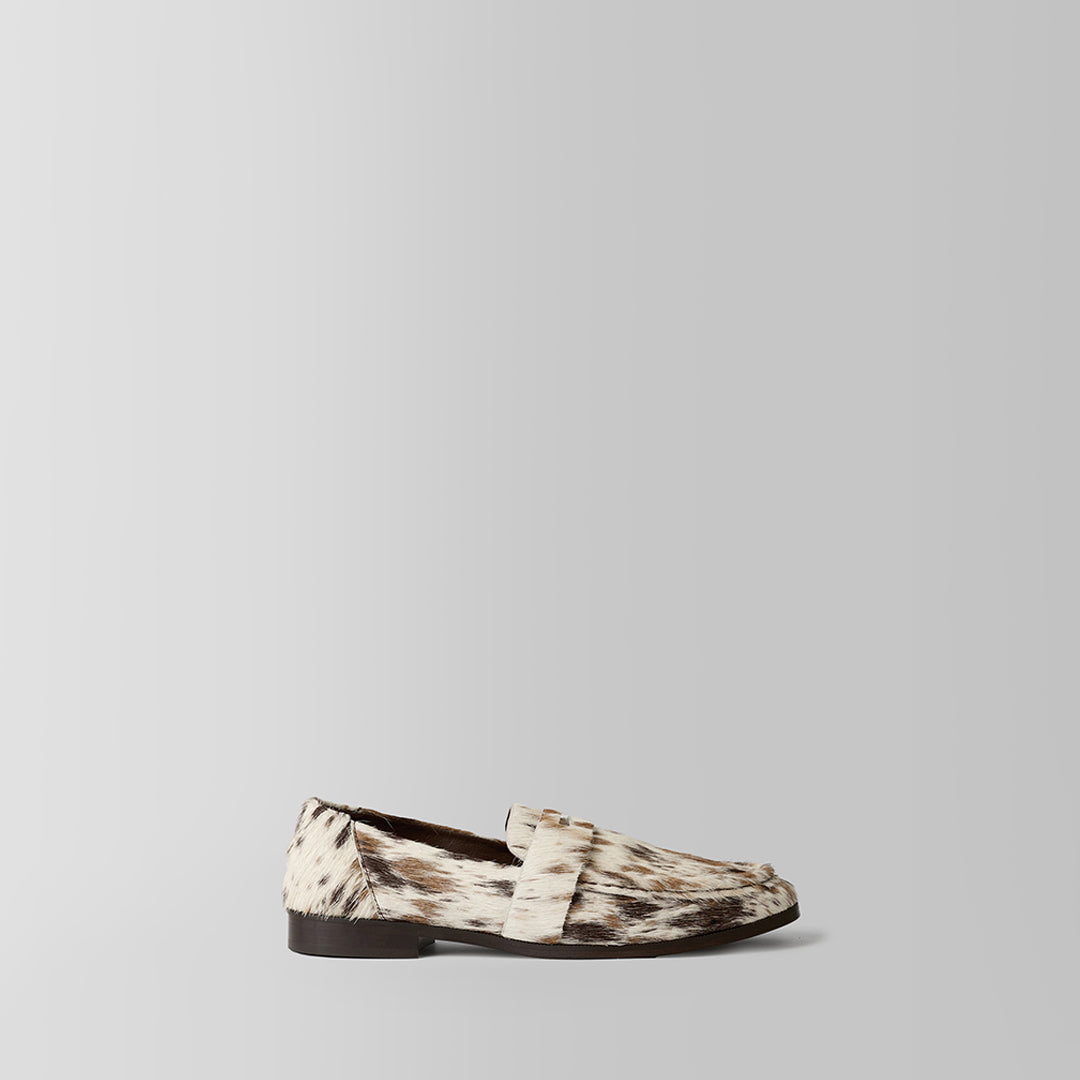 A single loafer in a brown and beige animal print pattern, shown in a side profile against a light gray background.