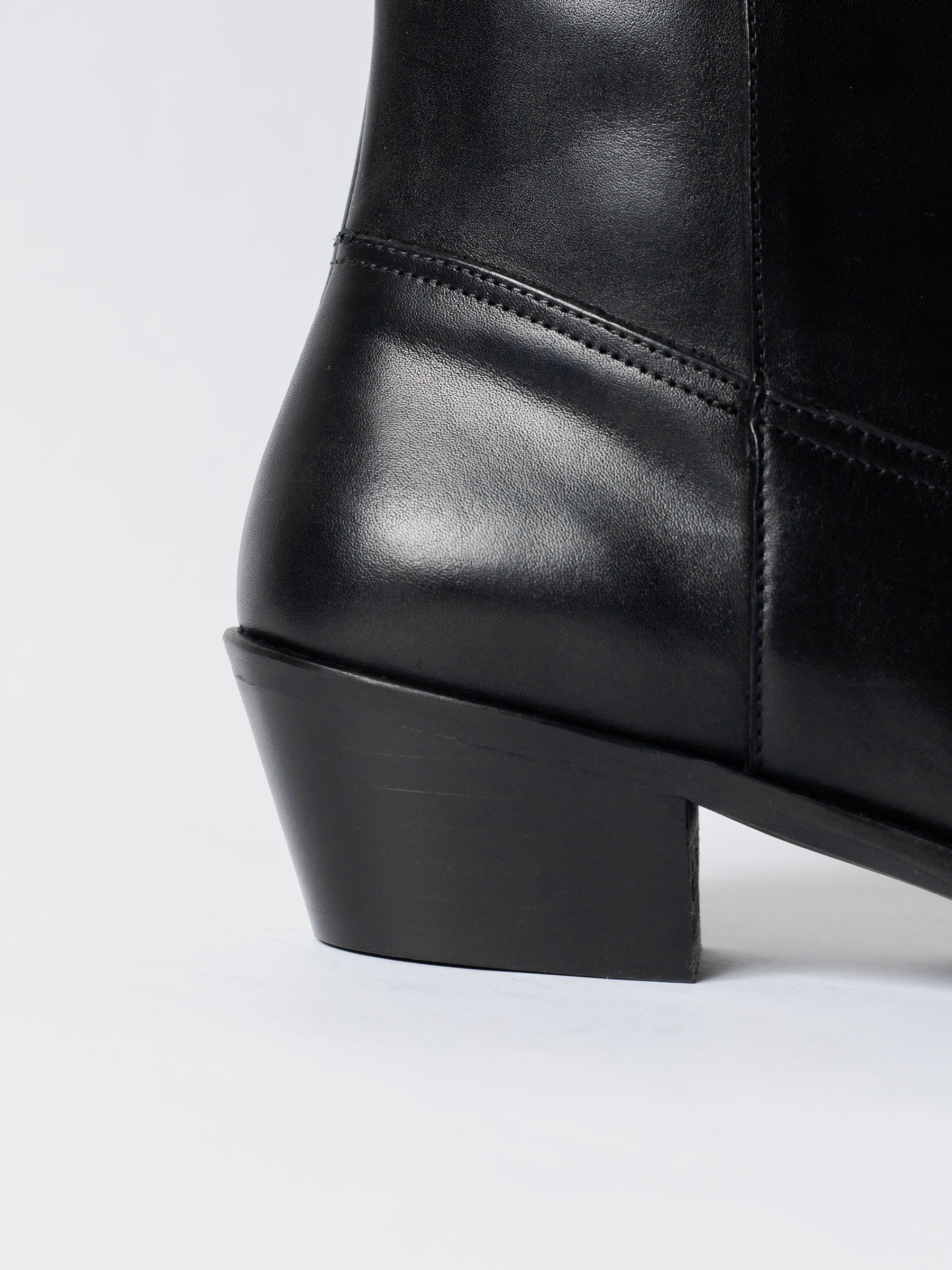 Close-up of a black leather boot on a white background