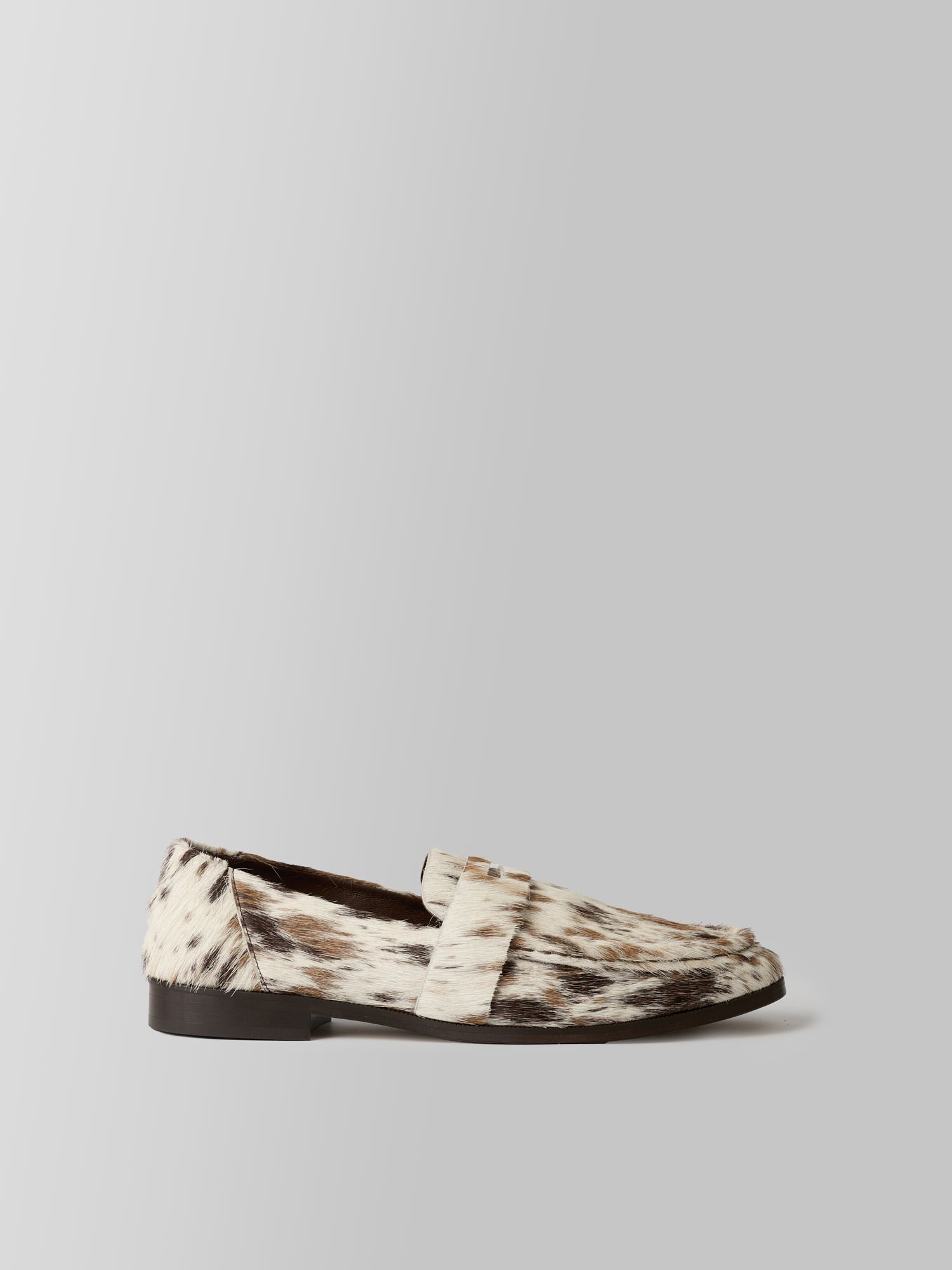 Loafer with cow print pattern on a light gray background