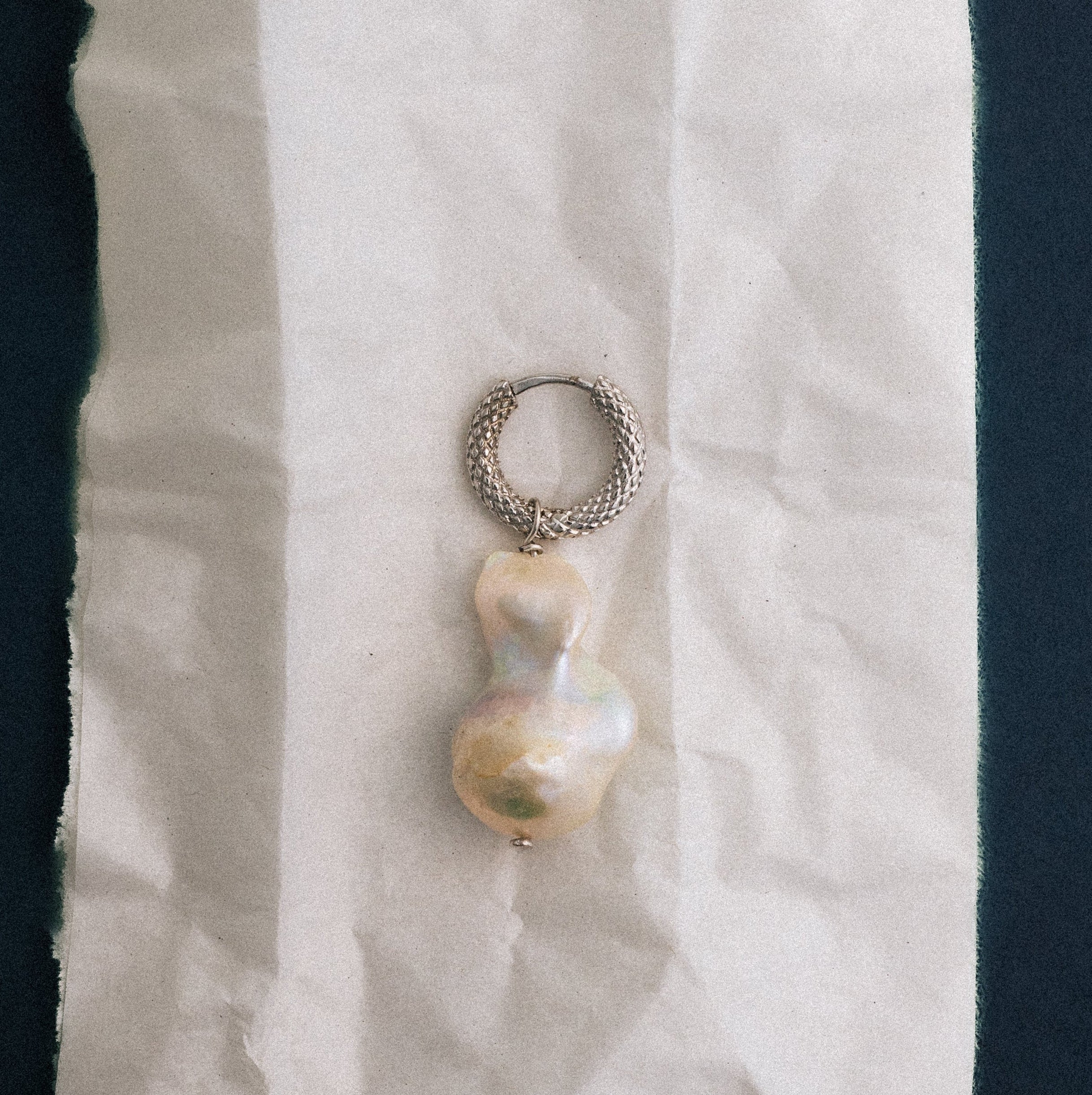 Pearl earring on a white cloth against a dark background