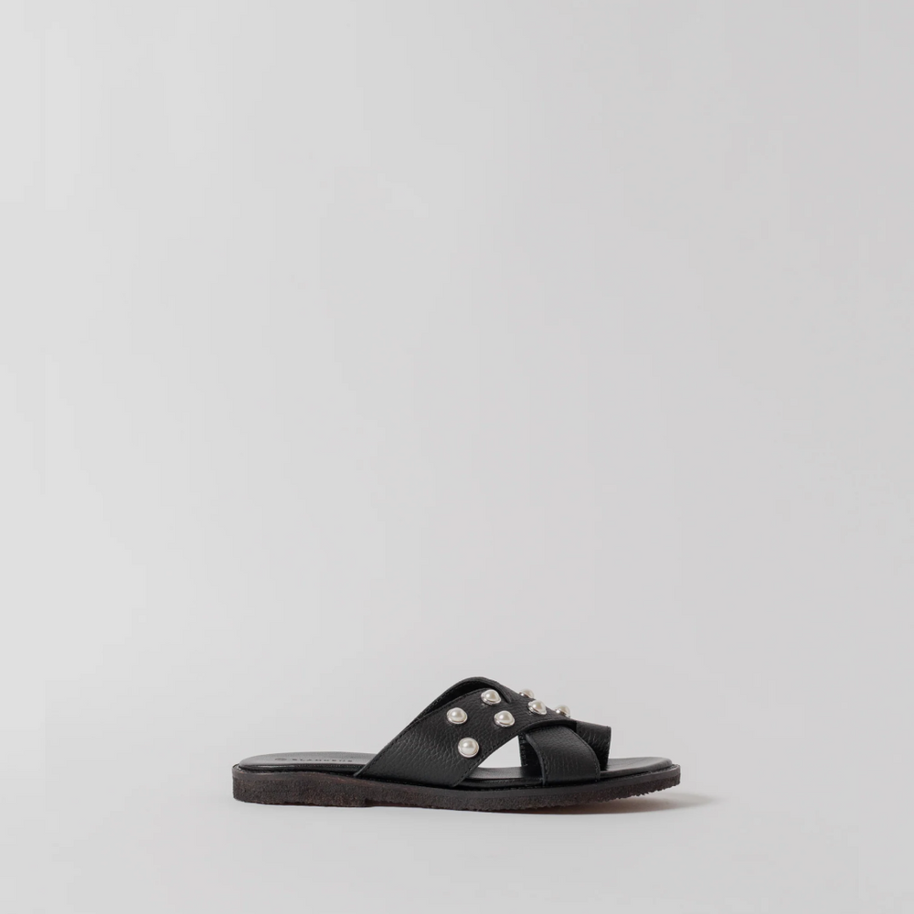 Black sandal with embellishments on a light gray background
