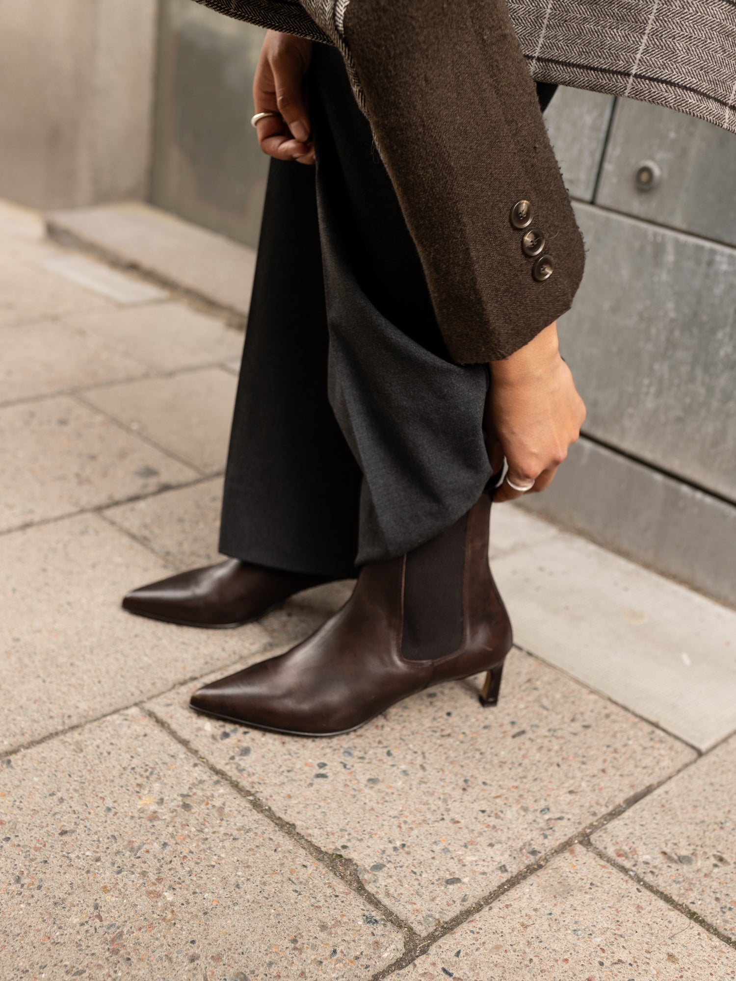 Person wearing brown ankle boots on a sidewalk