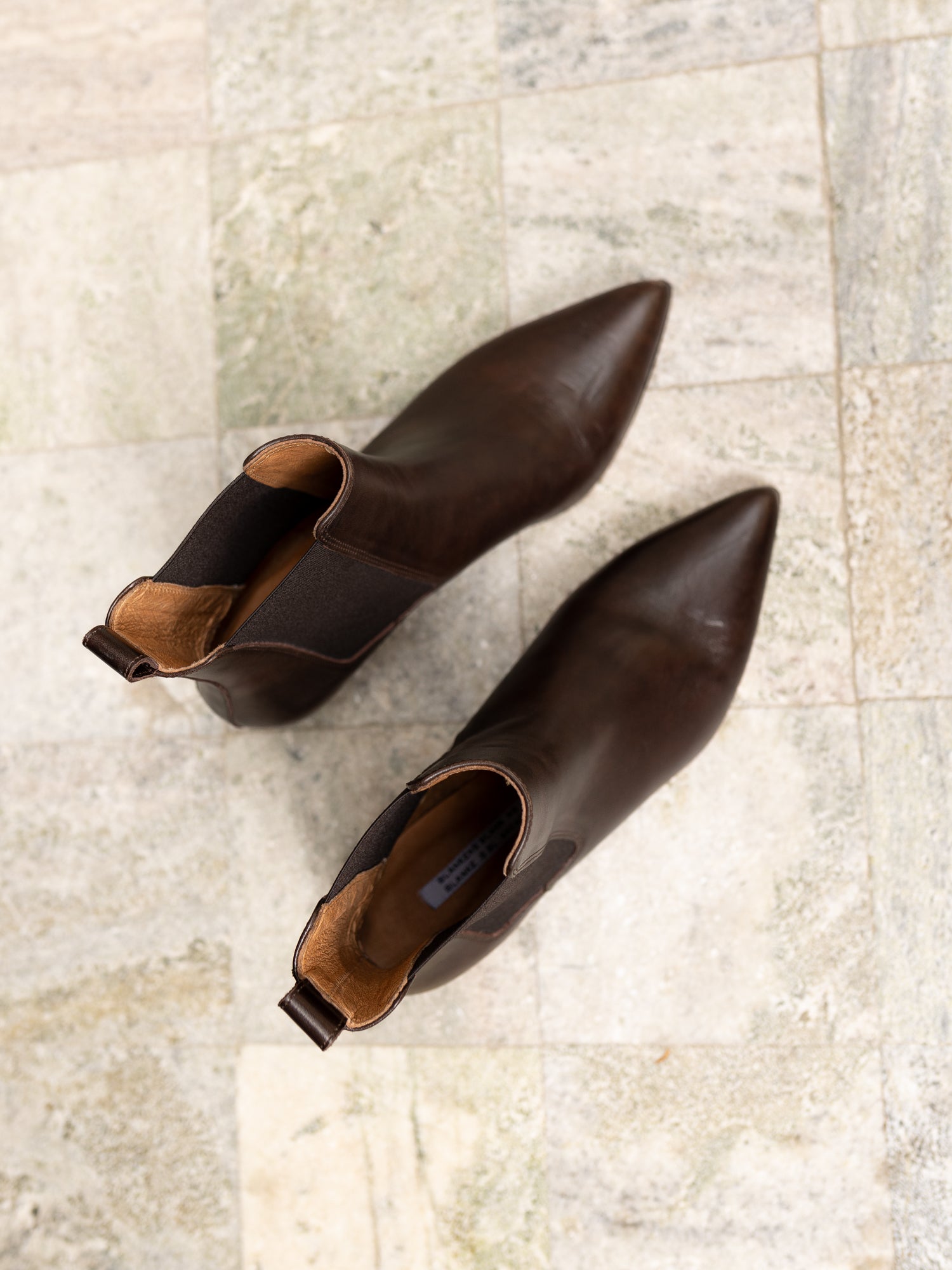 Pair of brown leather ankle boots on a light stone floor